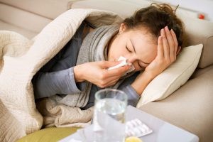 person laying down while sick holding tissues